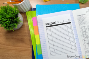 Interactive science notebook with an assessment tracker, divider tabs and school supplies on wood table